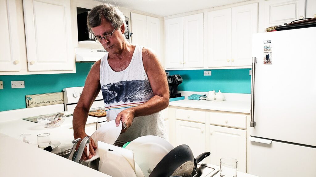 Man in business attire cleaning house in the kitchen...