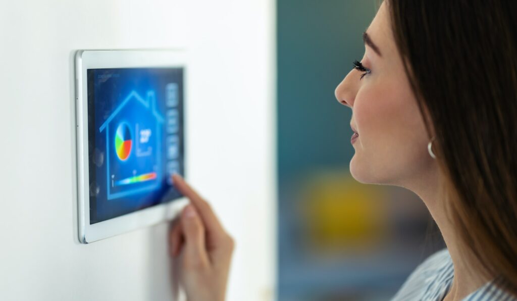 Pretty young woman using the home automation system on digital tablet to regulate the temperature.