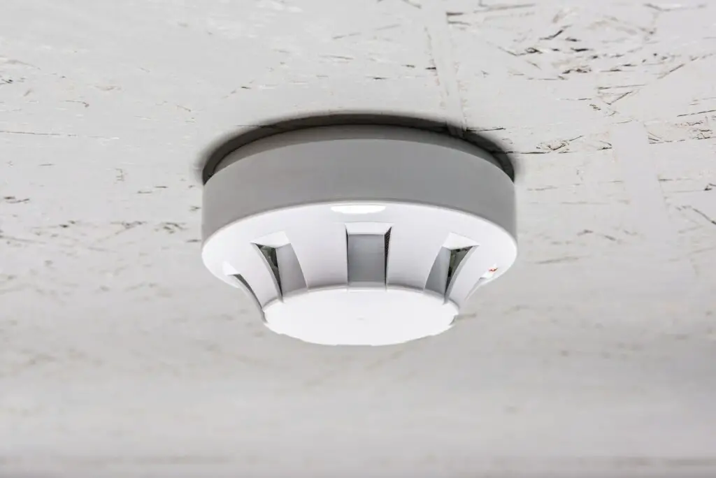 smoke detector of fire alarm on white ceiling at home