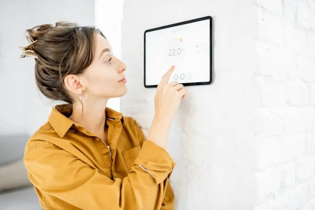 Woman controlling room temperature with a digital touch screen panel