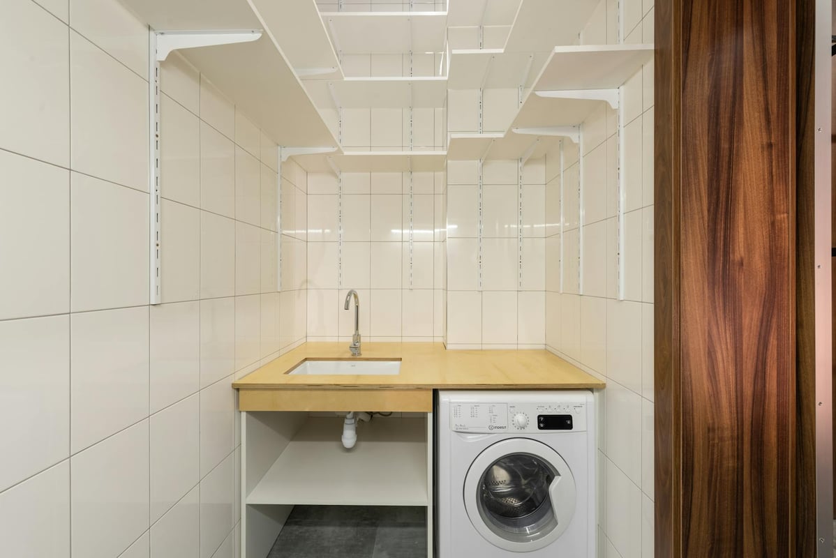 Clean and minimalist laundry room with washing machine and open shelving, ideal for small spaces.