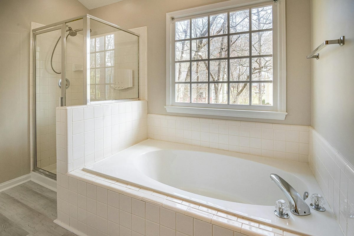 Spacious bathroom interior featuring a modern bathtub, shower, and large window with natural light.