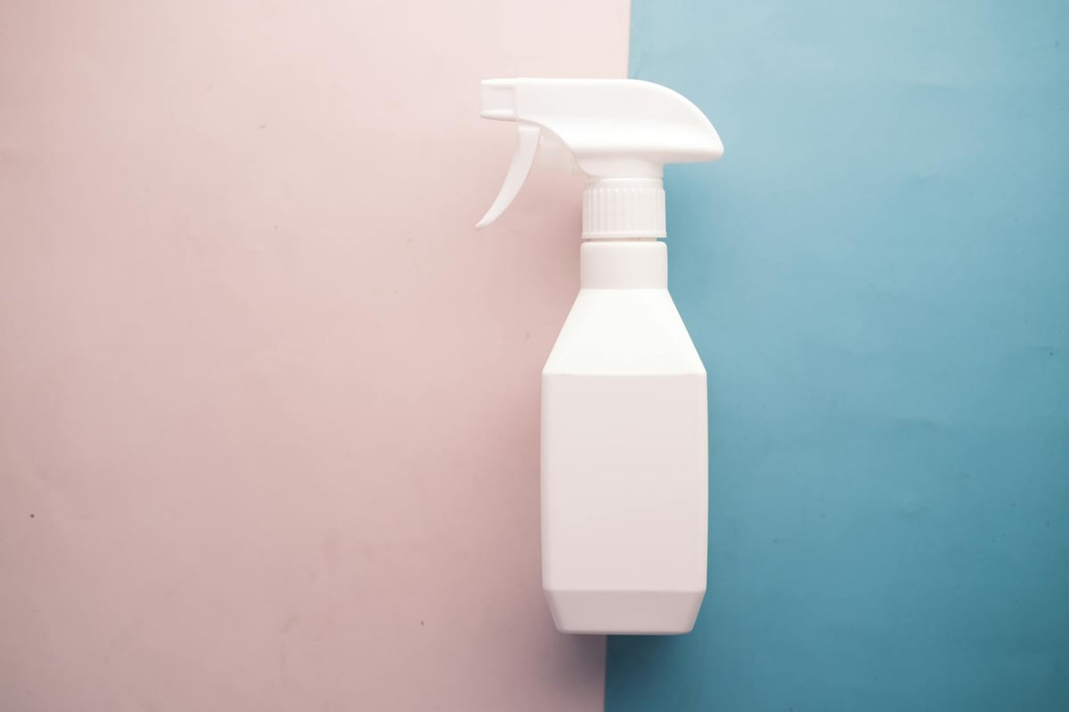 White spray bottle on pink and blue background with copy space, perfect for product mockups.