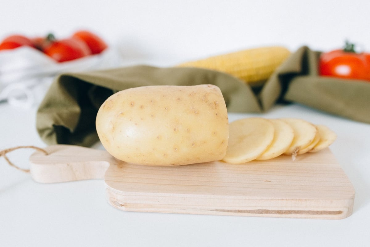 Fresh potato slices on a wooden board, ideal for culinary themes.