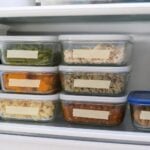 Leftovers divided into small, shallow labeled glass containers on a refrigerator shelf.