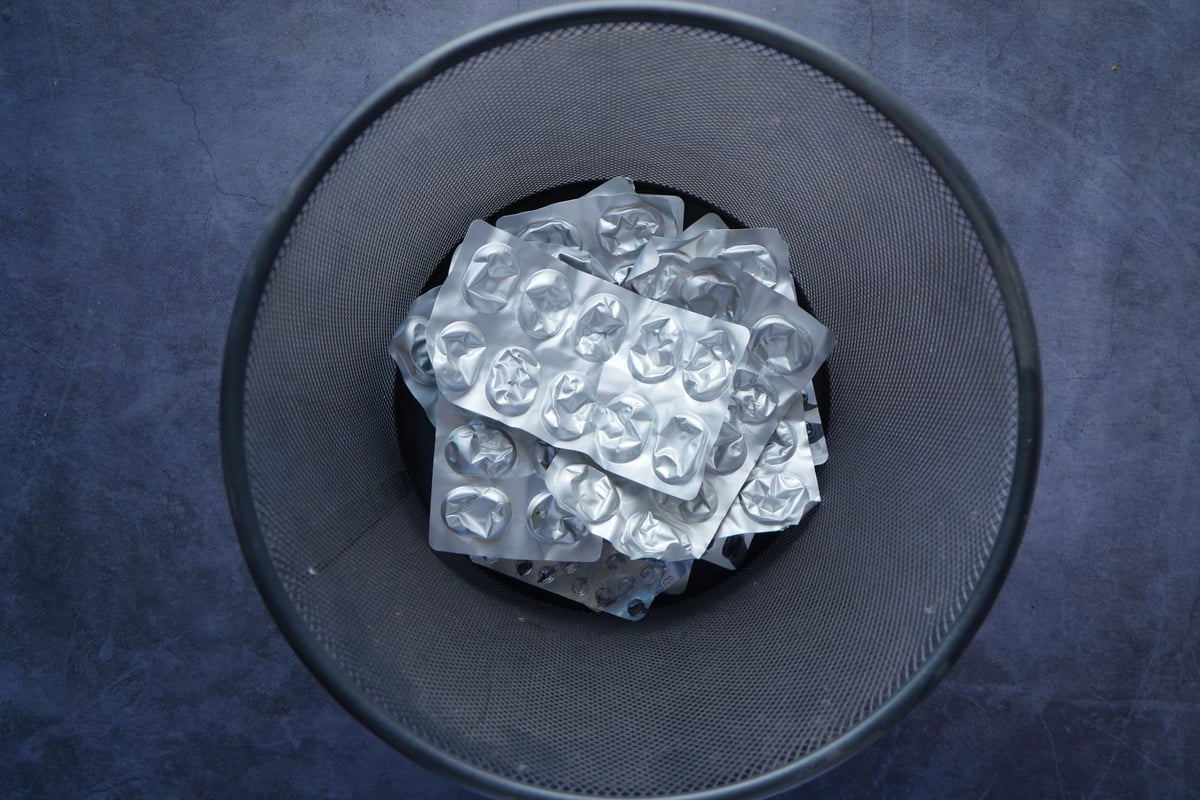 Overhead view of empty blister packs in a trash bin symbolizing waste and recycling.