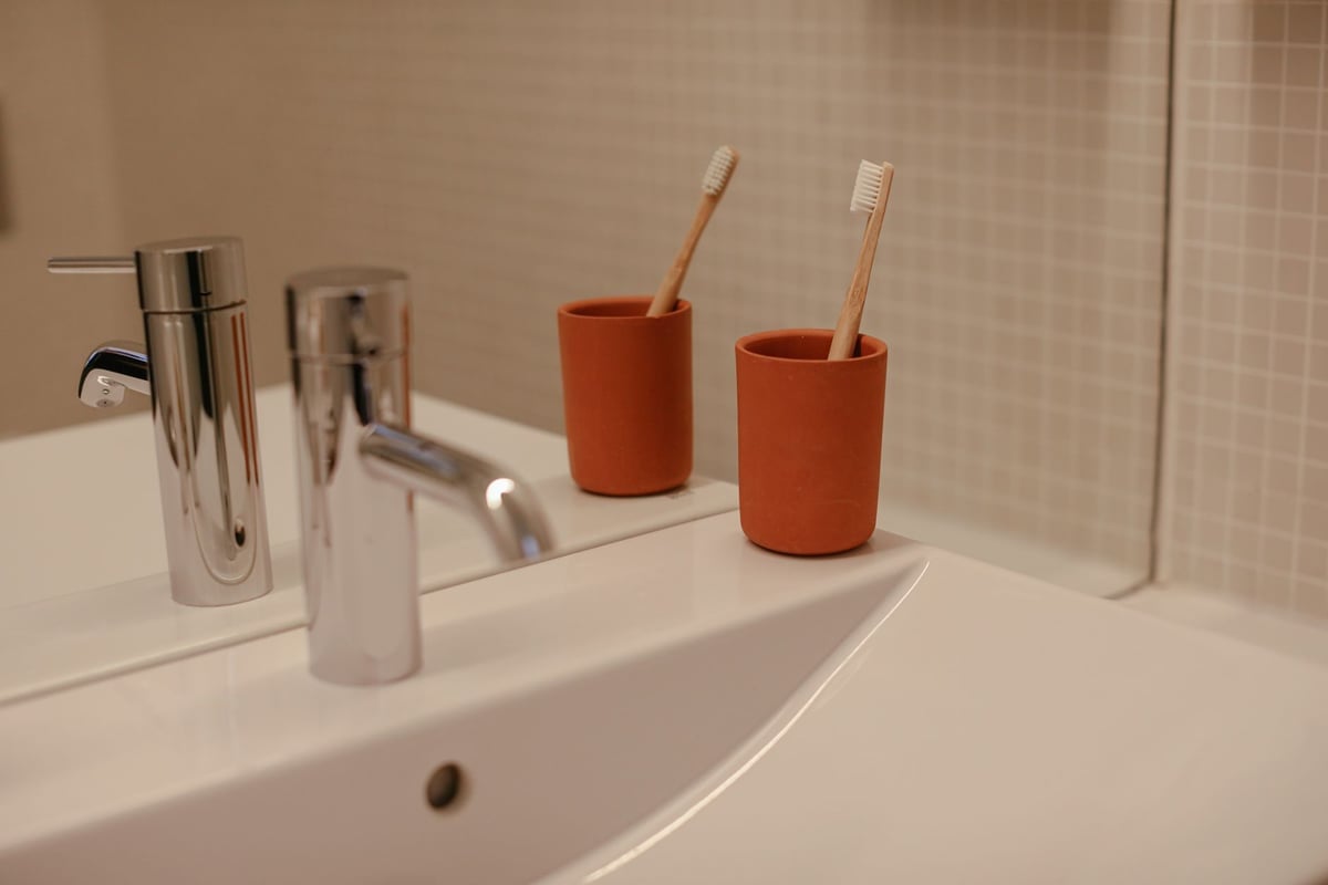 Polished bathroom sink with red cups and toothbrushes, featuring elegant design elements.